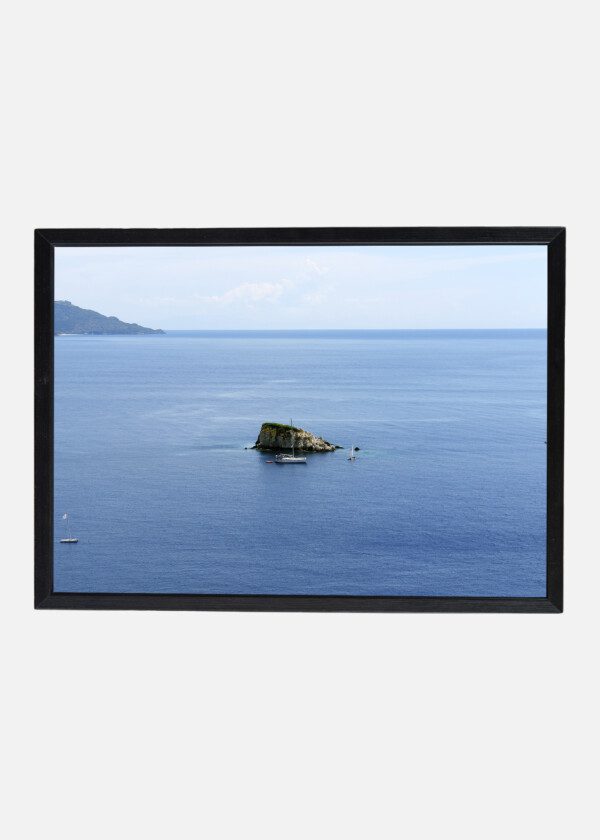 SMALL ISLAND AND A YACHT IN THE BLUE BAY OF THE IONIAN SEA IN GREECE