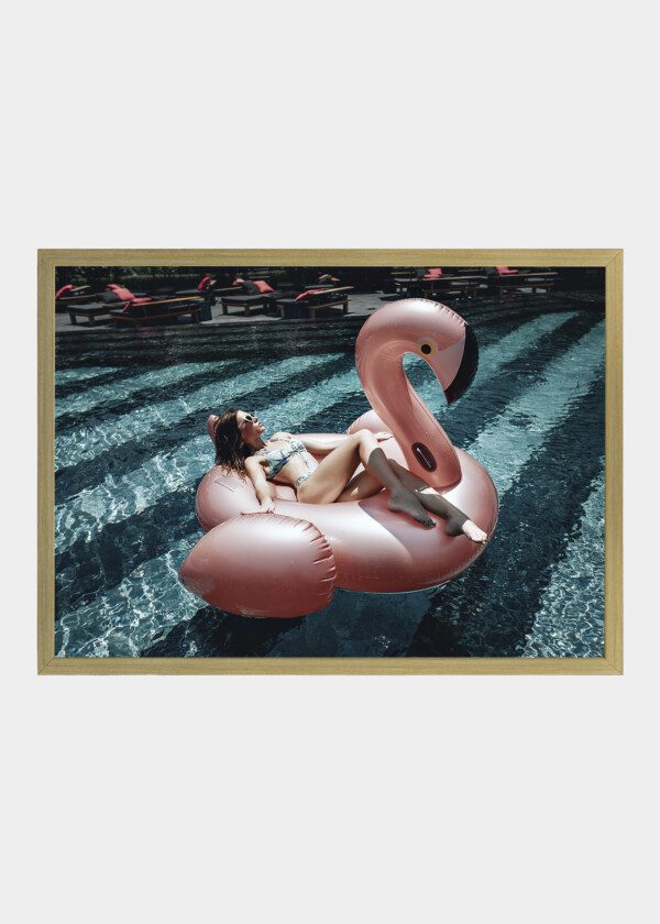 CUTE GIRL IN SUNGLASSES HAS FUN IN THE BLUE POOL WITH PINK INFLATABLE FLAMINGO-RING