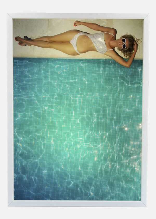 BEAUTIFUL YOUNG WOMAN RELAXING IN THE SWIMMING POOL