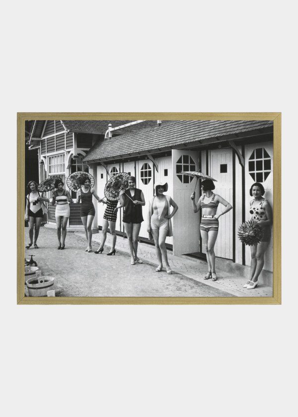 FRENCH WOMEN POSE IN THE LATEST FASHIONABLE BATHING SUITS OUTSIDE THEIR BEACH CABANAS AT DIEPPE