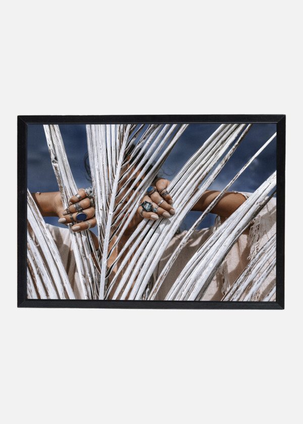 CLOSE UP OF BEAUTIFUL YOUNG TRIBAL STYLE WOMAN WITH LOTS OF ACCESSORIES BEHIND PAINTED WHITE PALM LEAF
