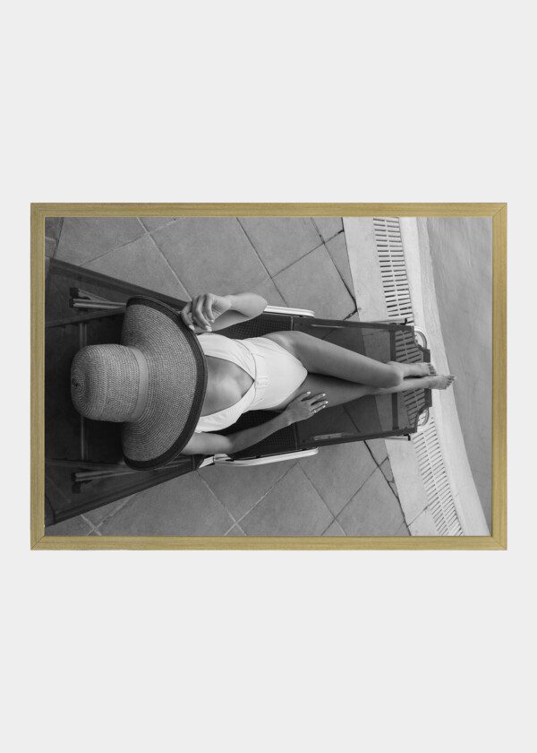 BEAUTIFUL SEXY BLONDE GIRL LIES ON A LOUNGER BY THE POOL SUNBATHES IN A STYLISH WHITE RETRO SWIMSUIT